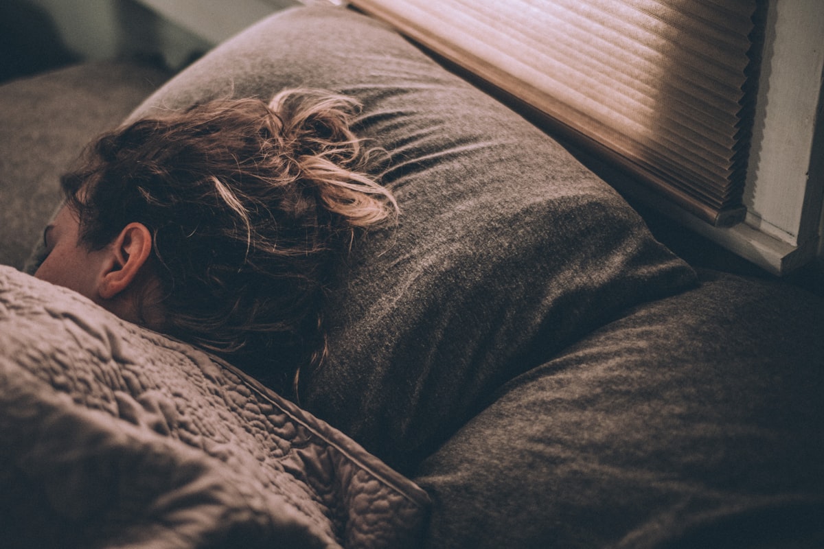 Vrouw slaapt diep onder dekens: CBN olie als mogelijke ondersteuning bij slaap